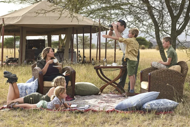 Família com crianças relaxando no acampamento de safari na savana africana