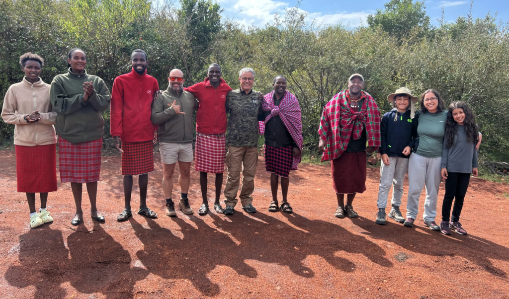 Grupo diverso de turistas e guias posando juntos em área de savana com vegetação verde